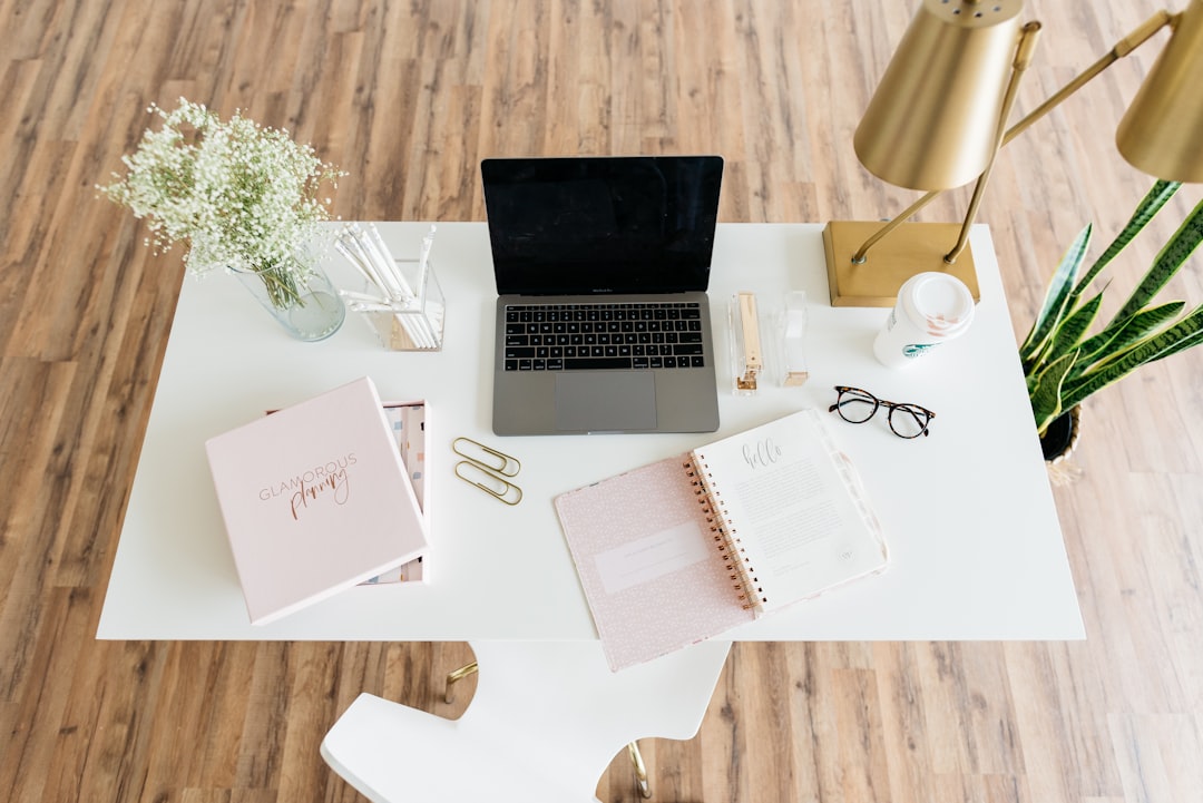 Bureau moderne avec ordinateur portable, plantes et fournitures de bureau sur une table en bois. Ambiance professionnelle et organisée.