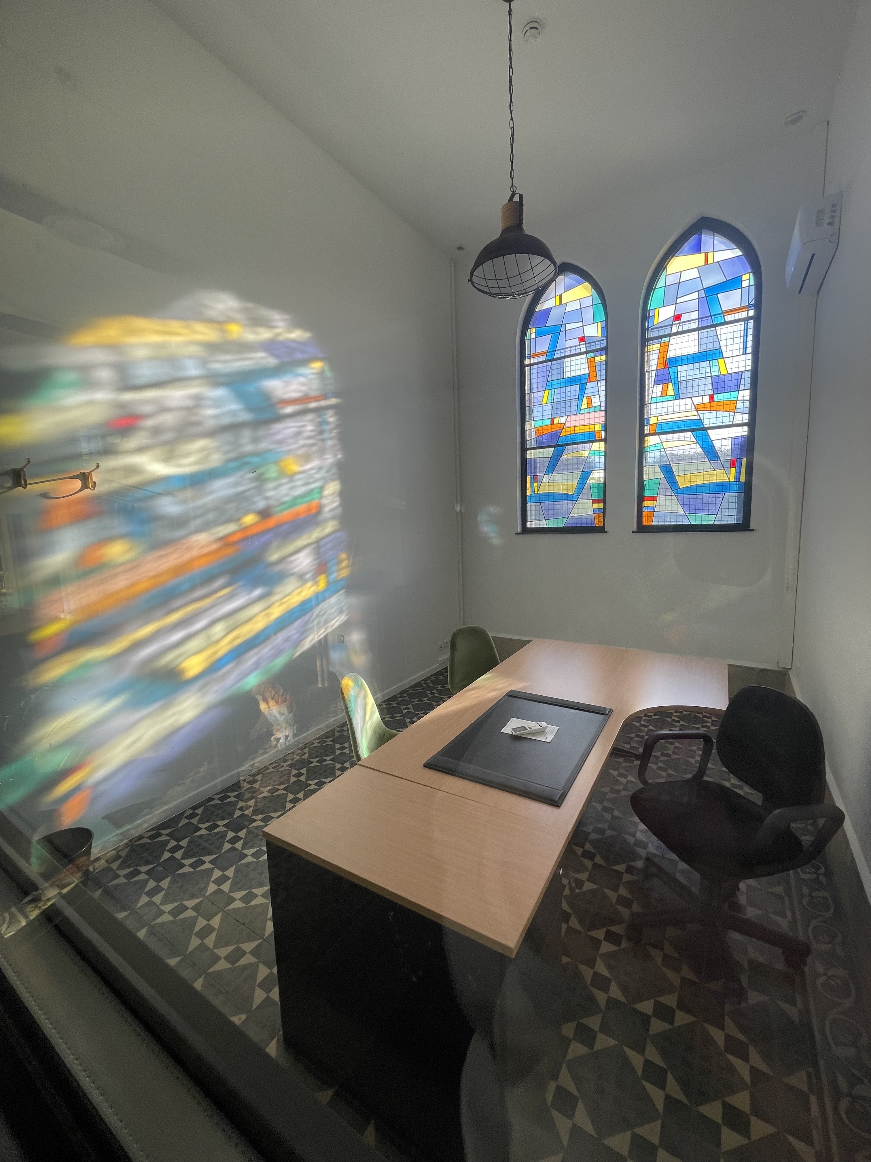 Bureau privatif en coworking à Mons avec éclairage naturel et fenêtres en vitrail coloré.