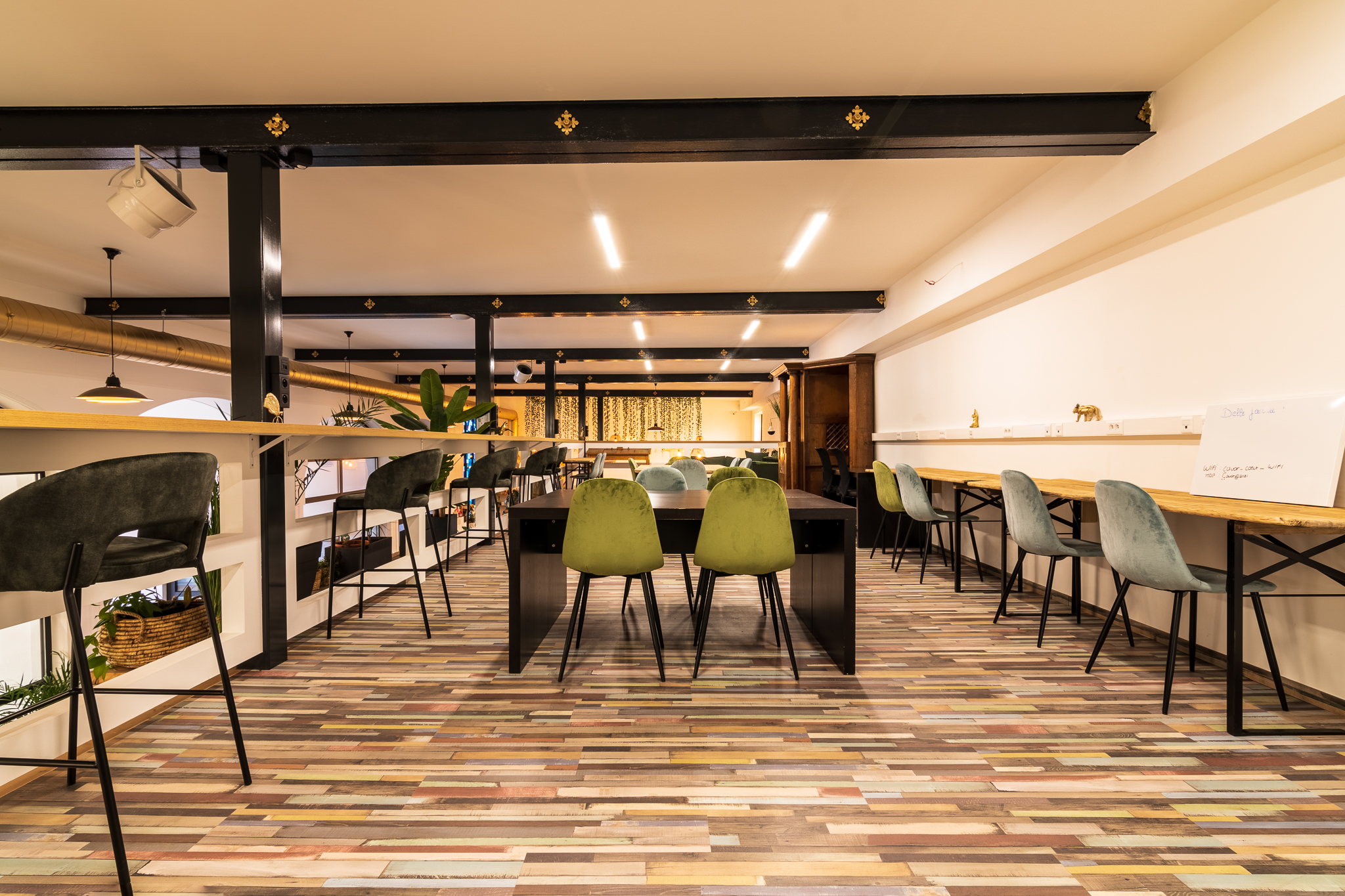 Intérieur d'un espace de coworking chaleureux avec des bureaux et des chaises colorées, éclairage moderne et ambiance conviviale.