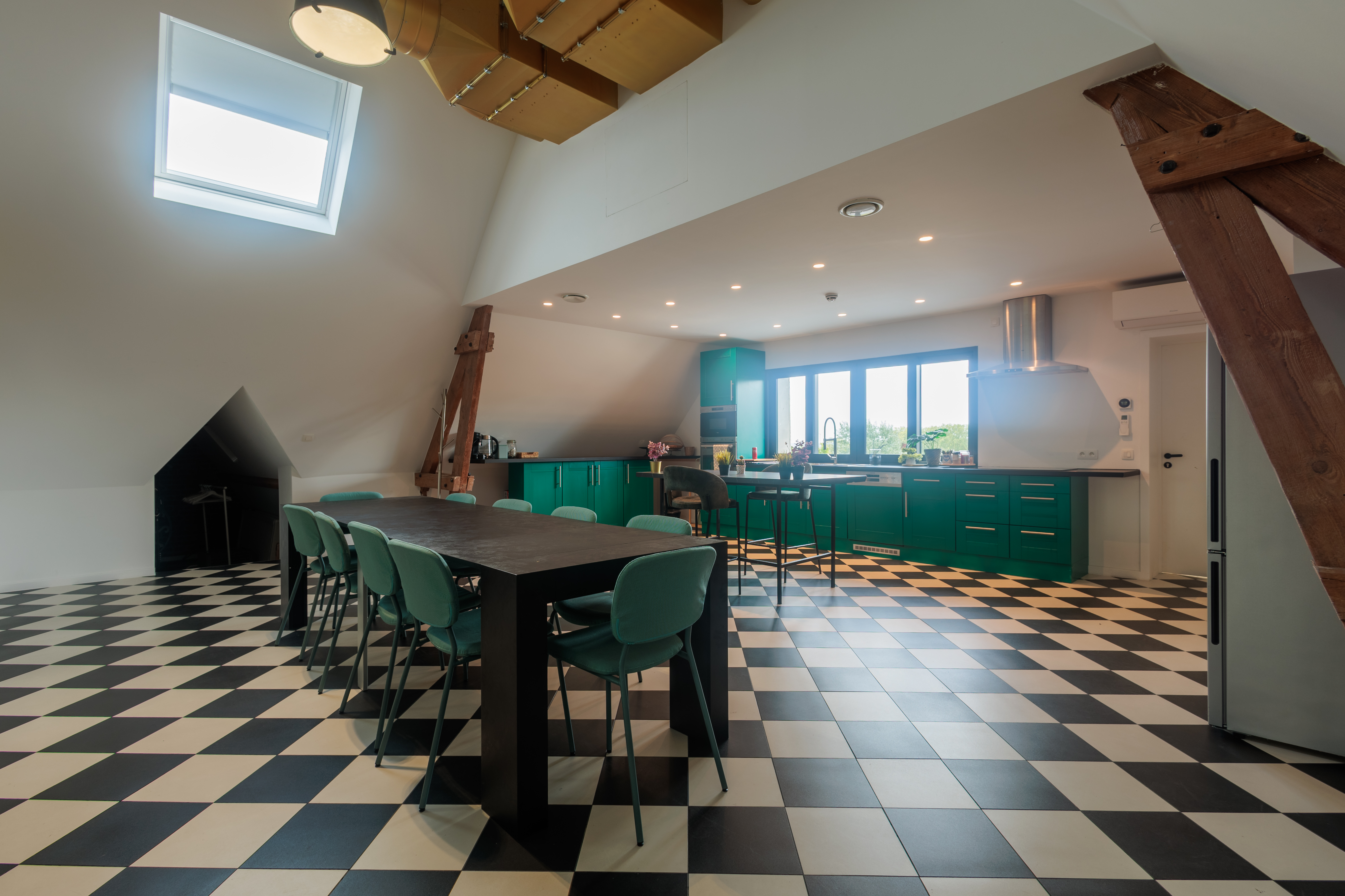 Cuisine d'un espace de coworking avec des meubles modernes et une ambiance conviviale, revêtement de sol en damier, vue sur l'extérieur.