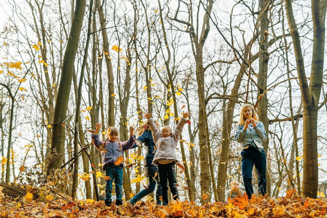 Des enfants s'amusent en jouant avec des feuilles d'automne dans une forêt.