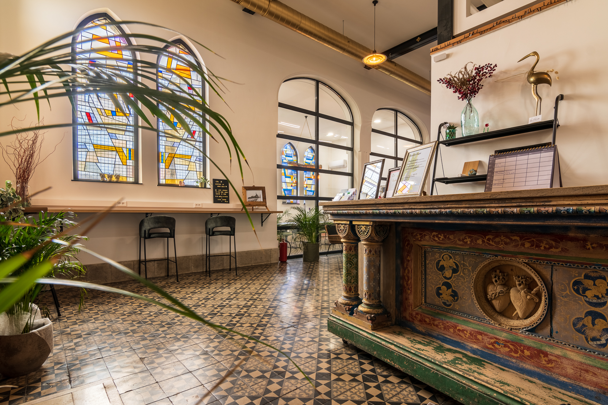Intérieur chaleureux d'un espace de coworking avec des fenêtres en vitrail et un comptoir coloré, ambiance conviviale.
