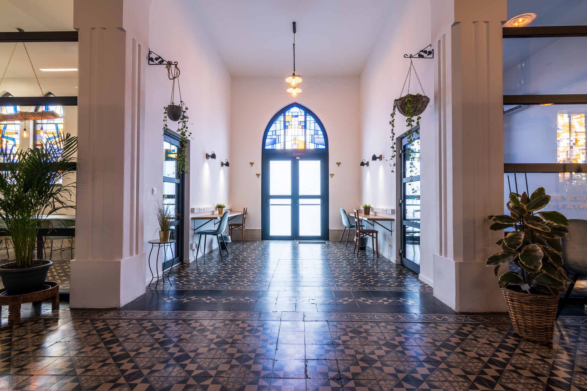 Intérieur d'un espace de coworking à Mons, avec des chaises et tables, éclairage chaleureux et détails architecturaux.