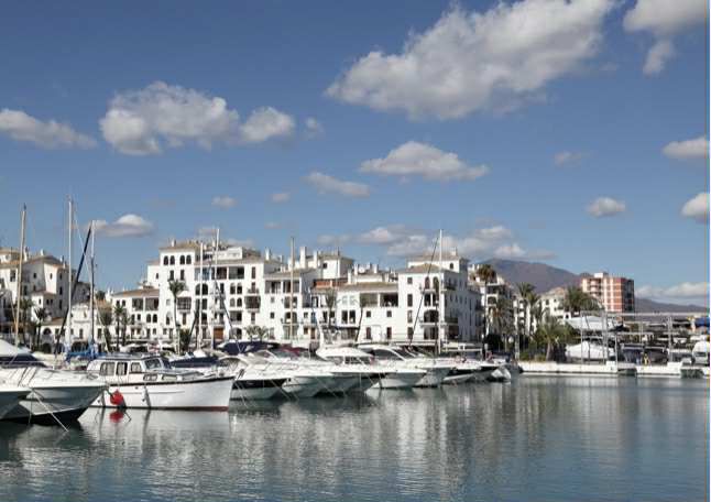 Vue pittoresque du port avec des yachts et des bâtiments blancs sur la Costa del Sol sous un ciel ensoleillé.