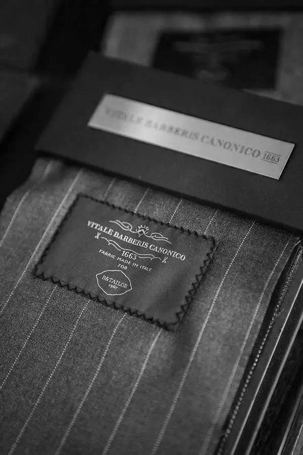 Échantillon de tissu avec étiquette "Vitale Barberis Canonico 1663", présentant un motif à rayures.